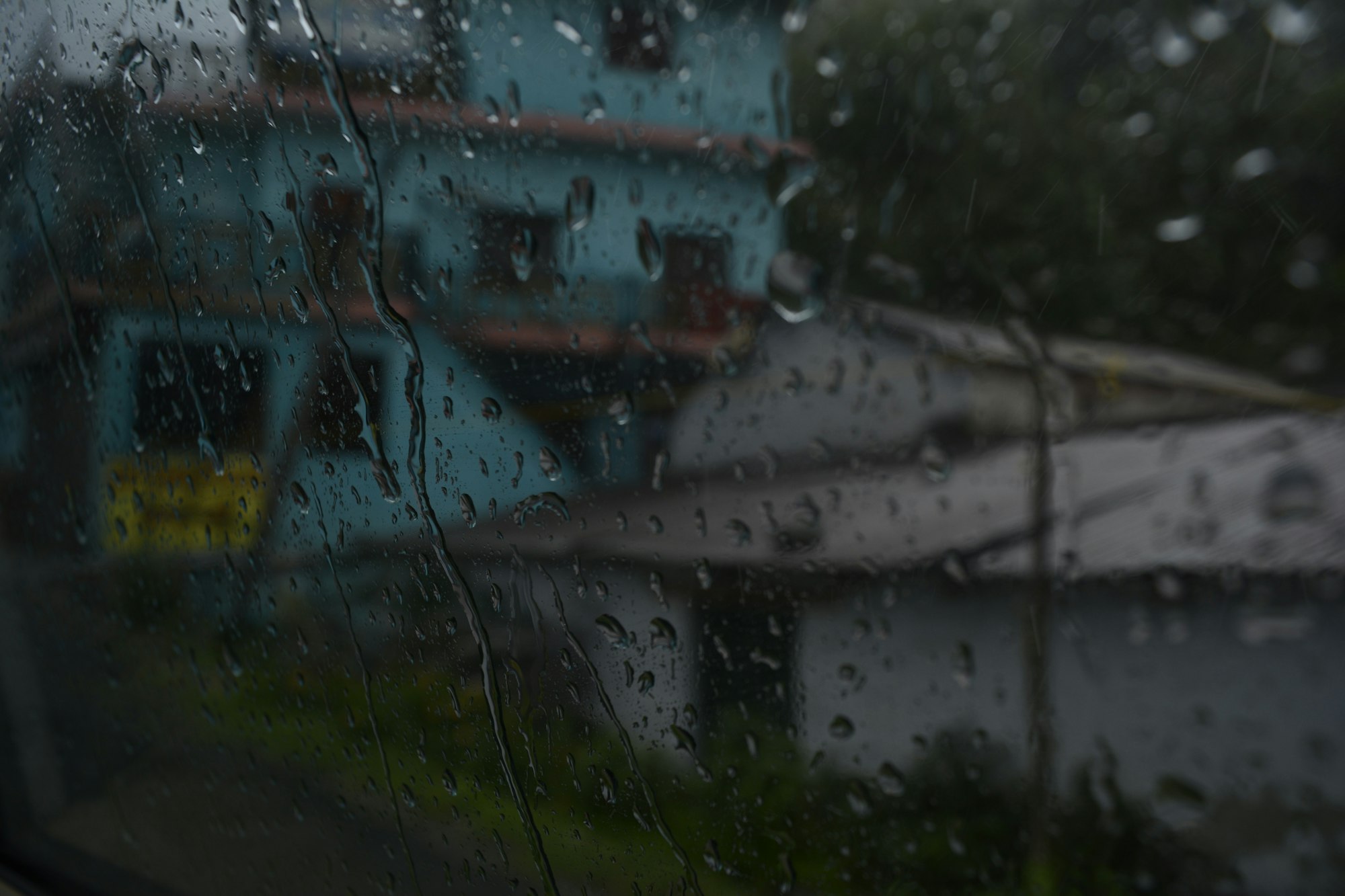 Rain streaking down a window with a house beyond
