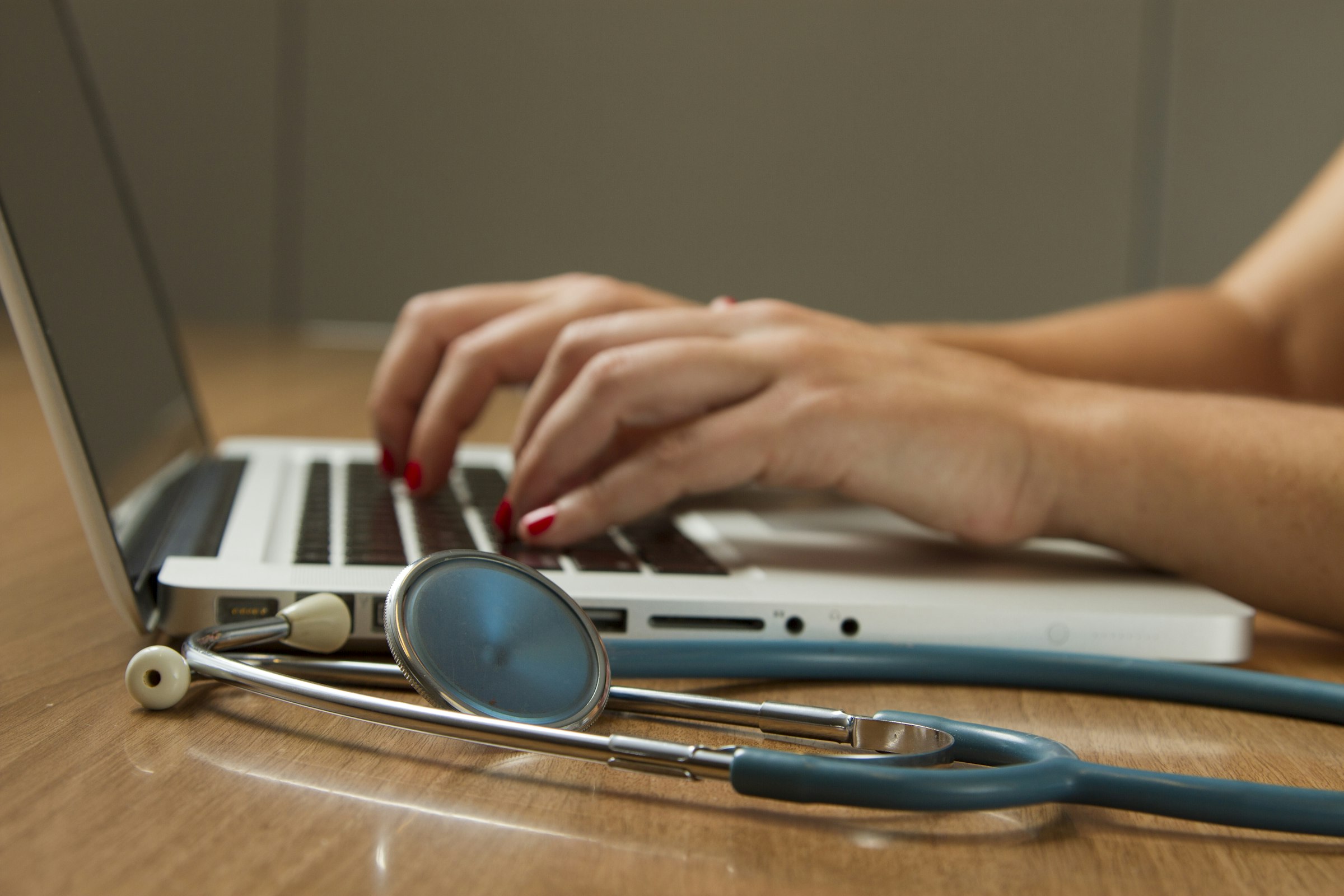 A stethoscope and laptop on a wooden desk